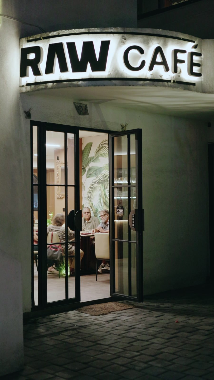 RAW Café sign at night, doors open onto the room